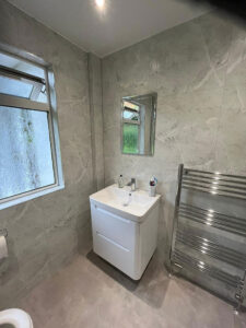 a wall-hung vanity sink unit and chrome towel radiator